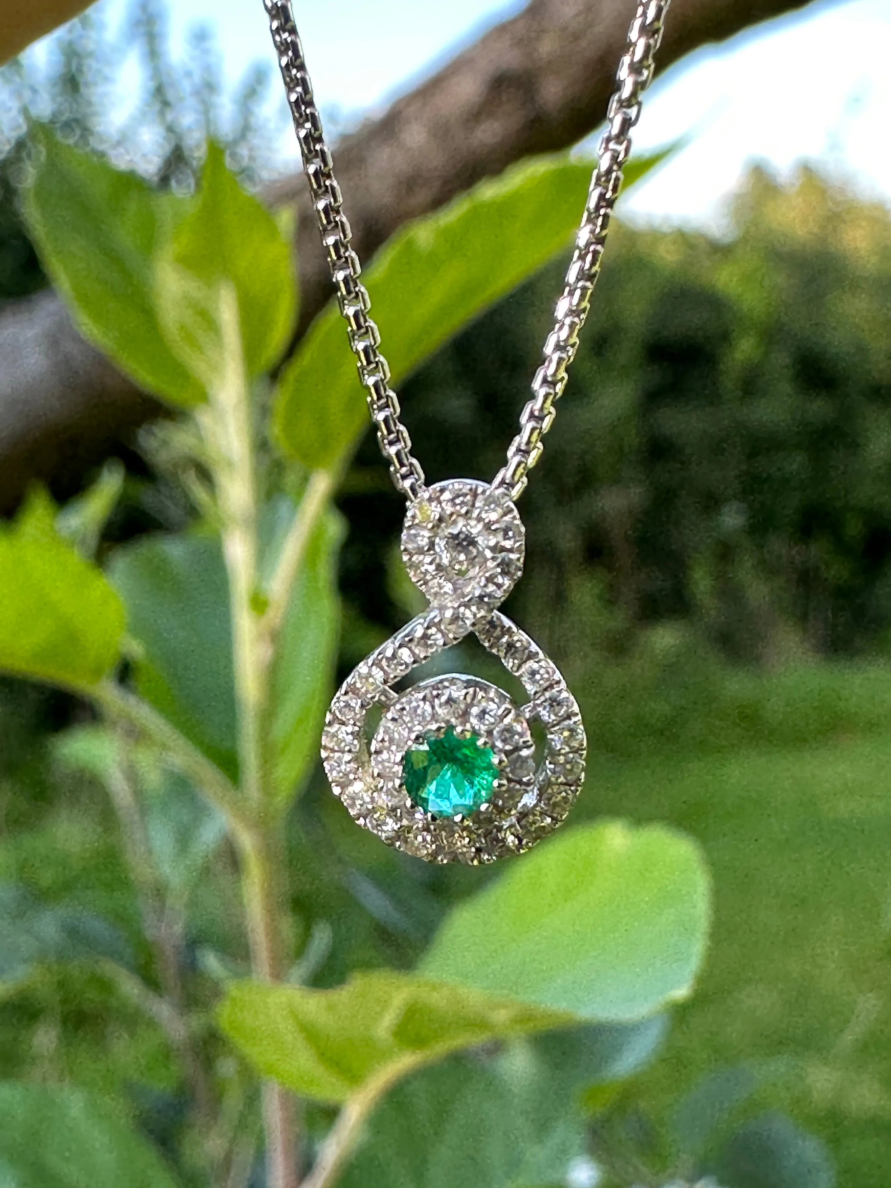 18ct white gold round cut emerald and diamond halo style necklace